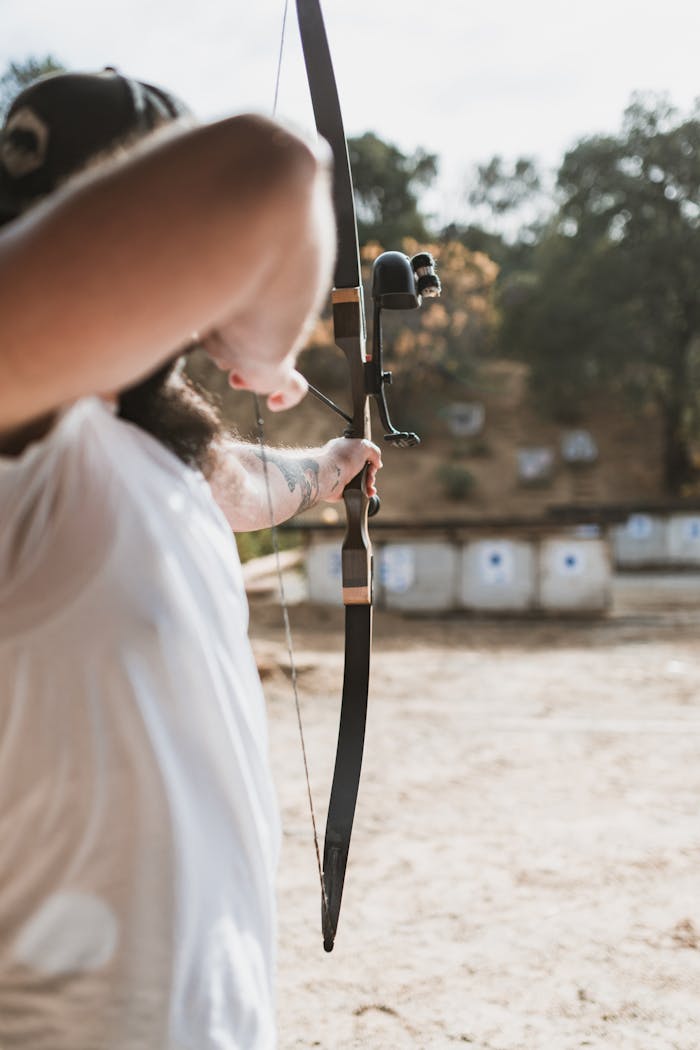 Home Adult practicing archery at outdoor range with traditional bow.